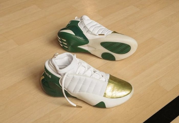 Side view of James Harden's white, green, and gold adidas shoes.